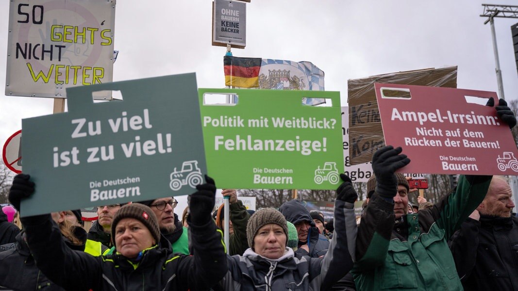 Bei einer Großkundgebung in Berlin halten einige Landwirte Protest-Schilder hoch.
