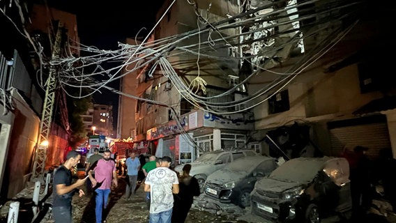 Libanon, Beirut: Menschen versammeln sich in der Nähe eines zerstörten Gebäudes. © dpa Bildfunk Foto:  Hussein Malla