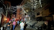 Libanon, Beirut: Menschen versammeln sich in der Nähe eines zerstörten Gebäudes. © dpa Bildfunk Foto:  Hussein Malla