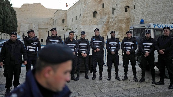 Palästinensische Polizisten stellen sich am Heiligabend in der Stadt Bethlehem im Westjordanland neben der Geburtskirche in Bethlehem auf. © dpa-Bildfunk/AP Foto: Matias Delacroix