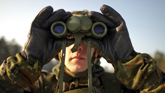 Ein Bundeswehr-Rekrut in Uniform blickt durch ein Fernglas. © dpa Foto: Arno Burgi