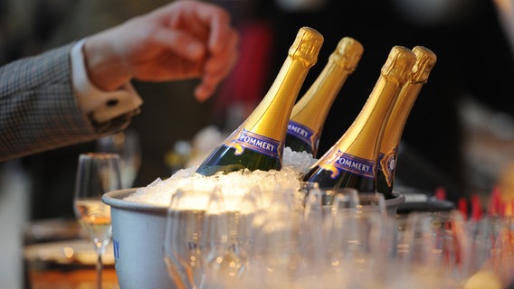 Eine Hand greift nach eisgekühlten Champagner-Flaschen © picture alliance / dpa Foto: Jens Kalaene