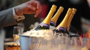 Eine Hand greift nach eisgekühlten Champagner-Flaschen © picture alliance / dpa Foto: Jens Kalaene