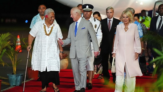 Der britische König Charles III. und Königin Camilla (r.) werden am Faleolo International Airport von Samoas Premierminister Fiame Naomi Mata'afa begrüßt. © dpa Bildfunk/PA Wire Foto: Aaron Chown