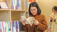 Eine Frau liest in einem Buch in einer chinesischen Bibliothek. © imago CFoto 