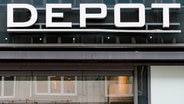 Das Logo der Handelskette Depot hängt über dem Eingang des Kaufhausesin der Innenstadt von Hamburg entlang. © Axel Heimken/dpa 