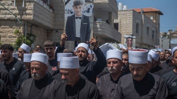 Angehörige der drusischen Minderheit trauern bei der Beerdigung ihrer Angehörigen in den israelisch kontrollierten Golanhöhen, nachdem bei einem Raketenangriff mehrere Kinder und Jugendliche getötet wurden. © dpa Foto: Ilia Yefimovich