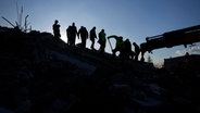Silhouette eines Rettungsteams, das in Antakya in der Türkei Überlebende des Erdbebens sucht © dpa-Bildfunk Foto: Khalil Hamra/AP/dpa