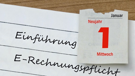 Auf einem Notizheft mit dem Schriftzug "Einführung E-Rechnungspflicht" liegt ein Kalenderblatt vom 1. Januar 2025. © picture alliance / ZB | Sascha Steinach 