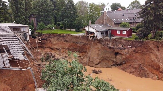 Im Ortsteil Blessem in Erftstadt steht nach einem Unwetter ein Gebäude an einer Erd-Abbruchkante. © dpa bildfunk Foto: David Young