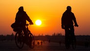 Zwei Radfahrer sind vor der untergehenden Sonne unterwegs. © picture alliance/dpa/dpa-Zentralbild Foto: Hauke Schröder