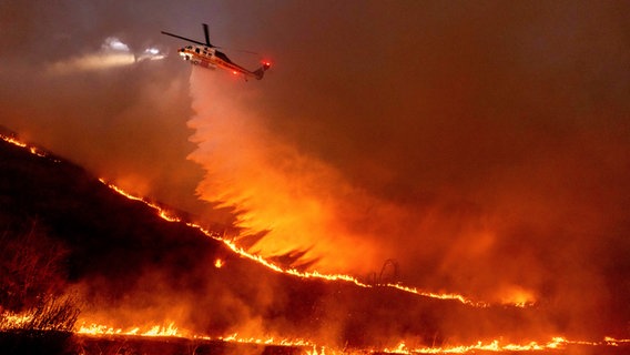 Ein Hubschrauber wirft Wasser auf das Kenneth-Feuer in den West Hills von Los Angeles. © dpa bildfunk/AP Foto: Ethan Swope