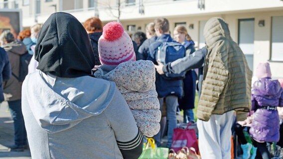 Geflüchtete stehen vor den Gebäuden einer Flüchtlingsunterkunft. © dpa Foto: Henning Kaiser