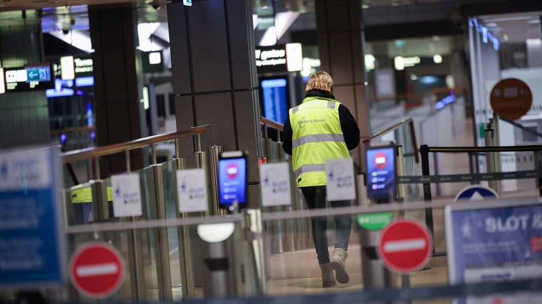 Eine Flughafenmitarbeiterin geht durch den menschenleeren Sicherheitsbereich.