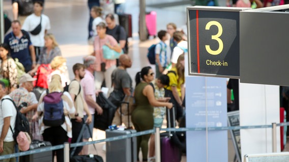 Menschen mit Koffern warten in einem Flughafen. © picture alliance 