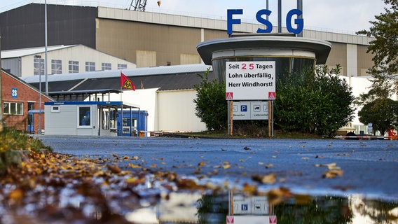 An der Einfahrt zur Werft der Flensburger Schiffbau-Gesellschaft steht ein Schild mit der Aufschrift „"Der Lohn ist seit 25 Tagen überfällig, Herr Windhorst!" © picture Alliance / Jörg Carstensen 