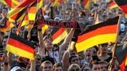 Fans der deutschen Fußball-Nationalmannschaft schwenken Fahnen bei einem Fanfest. © dpa bildfunk Foto: Kay Nietfeld