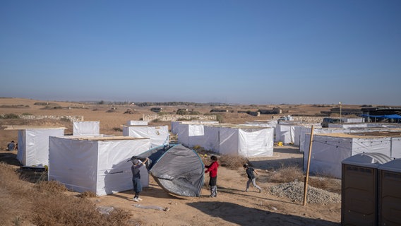 Israelische Kinder bauen ein Zelt während einer Veranstaltung im Rahmen des Laubhüttenfestes in der Nähe der Grenze zum Gazastreifen auf. © Ilia Yefimovich/dpa 