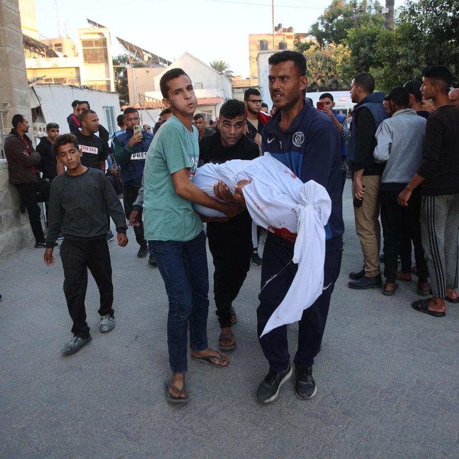 Menschen tragen einen toten, in Laken gehüllten Körper durch eine Straße in Gaza. © picture alliance / Anadolu | Omar El Qattaa Foto: piOmar El Qattaa