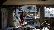 Ein palästinensischer Mann inspiziert ein von einem israelischen Angriff getroffenes Haus. © Mahmoud Issa/Quds Net News via ZUMA Press/dpa 