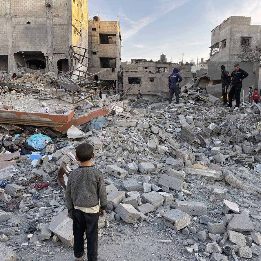 Mehrere Personen inspizieren zerstörte Gebäude im Gazastreifen. © picture alliance / Anadolu | Hasan N. H. Alzaanin Foto: Hasan N. H. Alzaanin