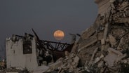 Der Vollmond geht am frühen Abend über zerstörten Gebäude im Zentrum des Gazastreifens auf. © picture alliance/dpa/APA Images via ZUMA Press Wire | Ali Hamad Foto: Ali Hamad