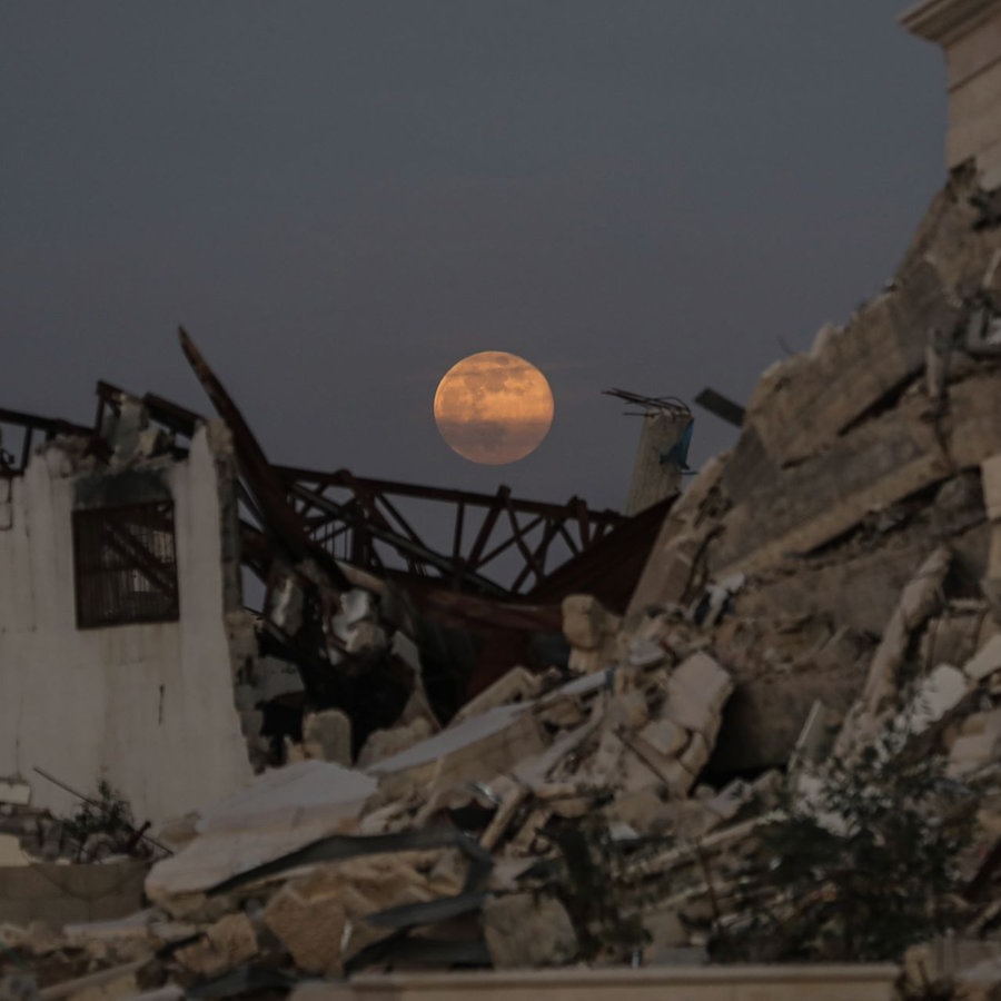 Der Vollmond geht am frühen Abend über zerstörten Gebäude im Zentrum des Gazastreifens auf. © picture alliance/dpa/APA Images via ZUMA Press Wire | Ali Hamad Foto: Ali Hamad