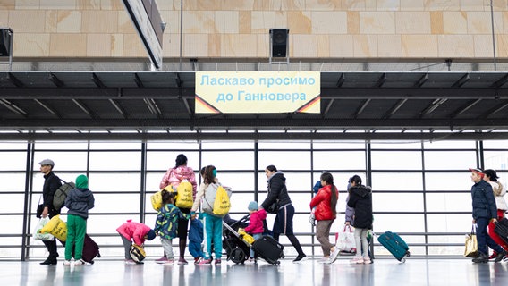 Geflüchtete Ukrainerinnen und Ukrainer bei ihrer Ankunft am Messebahnhof Laatzen. Auf einem Banner im Hintergrund steht "Willkommen in Hannover" auf Ukrainisch. © dpa Foto: Michael Matthey