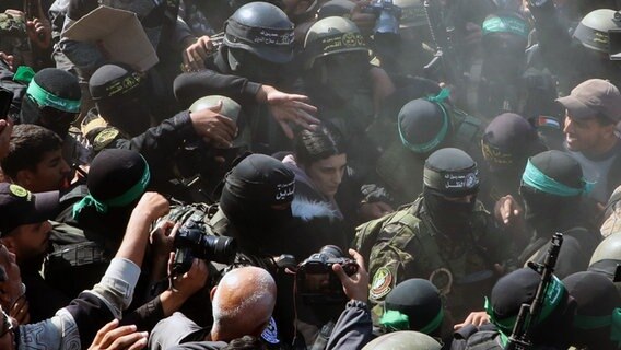 Die deutsch-israelische Soldatin Arbel Yehud wird von Kämpfern der Hamas und des Islamischen Dschihad eskortiert, als sie dem Roten Kreuz übergeben wird. © dpa-Bildfunk Foto: Naaman Omar/APA Images via ZUMA Press Wire/dpa