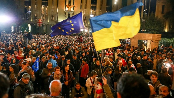 Demonstranten schwenken EU- und ukrainische Nationalflaggen, als sie sich während eines Protestes der Opposition gegen die Ergebnisse der Parlamentswahlen in Georgien versammeln. © Zurab Tsertsvadze/AP/dpa 