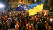 Demonstranten schwenken EU- und ukrainische Nationalflaggen, als sie sich während eines Protestes der Opposition gegen die Ergebnisse der Parlamentswahlen in Georgien versammeln. © Zurab Tsertsvadze/AP/dpa 