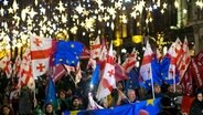 Demonstranten mit georgischen National- und EU-Fahnen nehmen an einer regierungskritischen Kundgebung vor dem Parlamentsgebäude in Tiflis teil. © Zurab Tsertsvadze/AP/dpa 