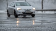 Gefrierender Schneematsch liegt vor einem Auto auf der Straße. © dpa Foto: Sebastian Gollnow