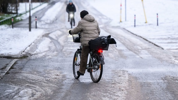 Eine Frau fährt mit dem Fahrrad über eine Straße. Diese Straße ist sehr glatt. © dpa Foto: Julian Stratenschulte