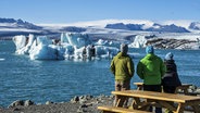 Touristen beobachten die Gletscherlagune Jökulsarlon am Vatnajökull, dem größten Gletscher auf Island. © picture alliance / imageBROKER | Andreas Werth 