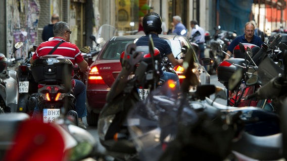 Motorradfahrer mit und ohne Helm fahren über eine Straße in Athen © Arno Burgi/dpa Foto: Arno Burgi