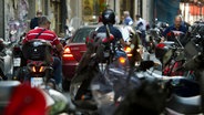 Motorradfahrer mit und ohne Helm fahren über eine Straße in Athen © Arno Burgi/dpa Foto: Arno Burgi