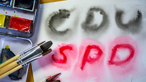 Mit Wasserfarben stehen die Namen der Parteien CDU und SPD auf einem Blatt Aquarellpapier. © dpa Foto: Hendrik Schmidt