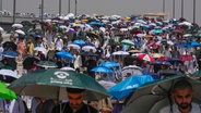 Muslimische Pilger benutzen Regenschirme, um sich vor der Sonne zu schützen, während sie an der Pilgerfahrt Hadsch in Mekka teilnehmen. © Rafiq Maqbool/AP/dpa 
