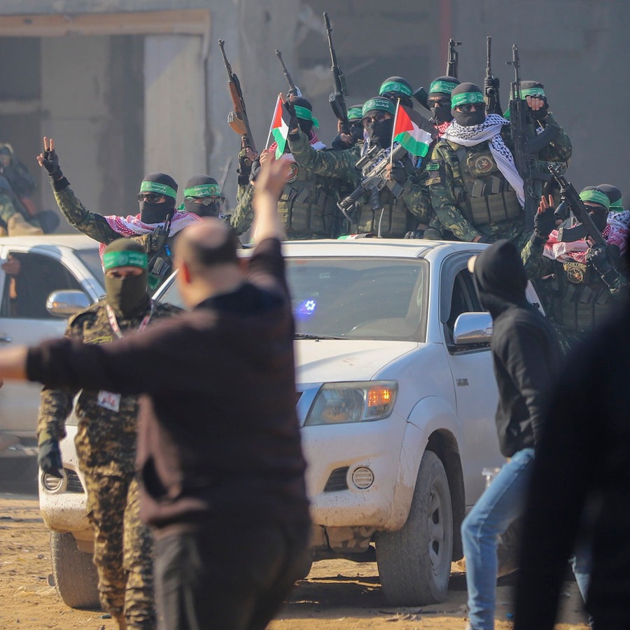 Hamas-Kämpfer werden begrüßt, als sie in Pick-up-Trucks am Ort der Übergabe der Geisel Agam Beger an das Rote Kreuz im Flüchtlingslager Dschabalija in Gaza-Stadt ankommen. © AP/dpa Foto: Mohammed Hajjar