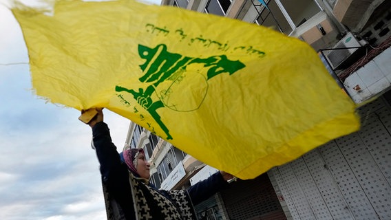 Eine Frau schwenkt eine Hisbollah-Flagge. © picture alliance/dpa/AP Foto: Hussein Malla