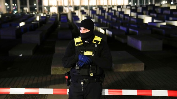 Ein vermummter Polizist steht nach einer Messerattacke vor dem Holocaust Mahnmal in Berlin. ©  Markus Schreiber/AP/dpa 