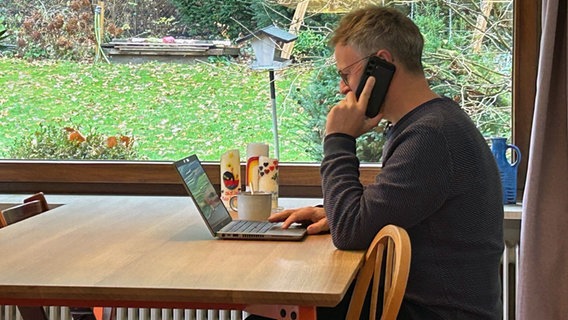 David Gohla aus Lüneburg sitzt vor seinem Laptop am Esstisch und telefoniert. Der Produktmanager arbeitet zum größten Teil im Homeoffice. © NDR / Ines Bellinger 