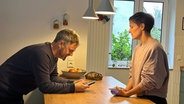 David und Julika Gohla stehen zu Hause am Küchentresen und besprechen die anstehenden Termine der Familie. Beide arbeiten zum großen Teil im Homeoffice. © NDR / Ines Bellinger 