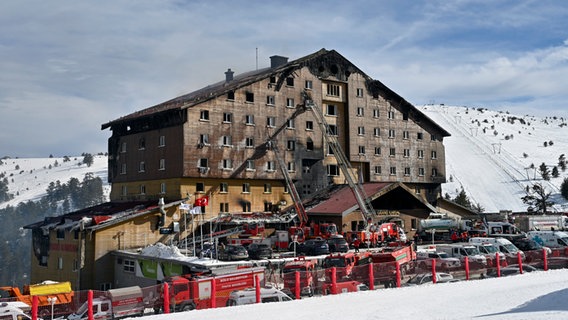 Feuerwehrleute arbeiten am Unglücksort nach dem Ausbruch eines Feuers in einem Hotel im Skigebiet Kartalkaya in der Provinz Bolu im Nordwesten der Türkei. © dia Photo/AP/dpa Foto: Mert Gokhan Koc