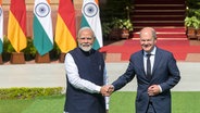 Indien, Neu Delhi: Der indische Premierminister Narendra Modi (l), und der deutsche Bundeskanzler Olaf Scholz (SPD) schütteln sich die Hände während der Deutsch-Indischen Regierungskonsultationen in Neu Delhi. ©  Uncredited/AP 