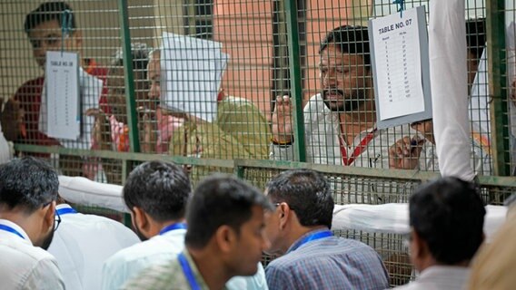 Wahlhelfer der politischen Parteien beobachten die Auszählung der Stimmen in einem Auszählungszentrum in Neu-Delhi. © Manish Swarup/AP/dpa Foto: Manish Swarup