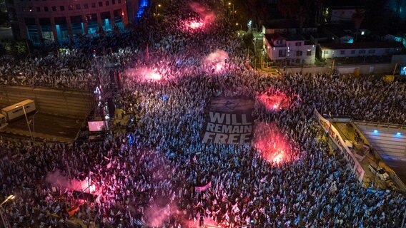 Tel Aviv: Israelis nehmen an einem Protest gegen die israelische Regierung teil und halten ein Banner auf dem "Will remain free" zu lesen ist. © AP/dpa Foto: Oded Balilty