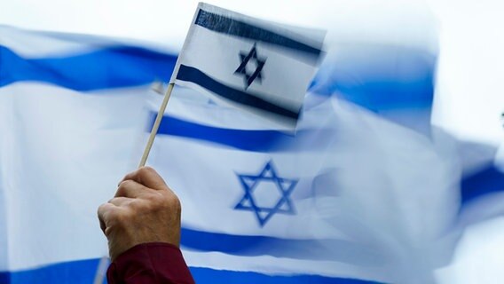 Eine Person hält eine Israel-Flagge auf einer Demonstration. © dpa-Bildfunk/AP Foto: Lindsey Wasson