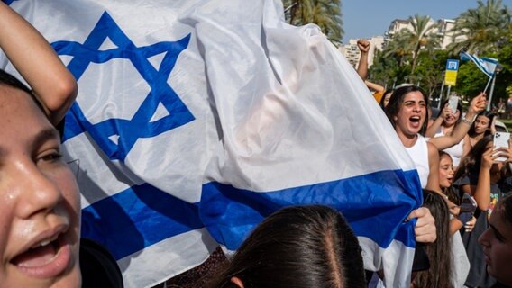 Israelis feiern mit israelischen Flaggen auf den Straßen nach der sicheren Rückkehr von vier israelischen Geiseln. © Sharon Eilon/SOPA Images via ZUMA Press Wire/dpa Foto: Sharon Eilon